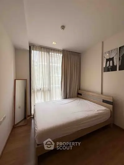 Cozy bedroom with large window and minimalist decor in modern apartment.