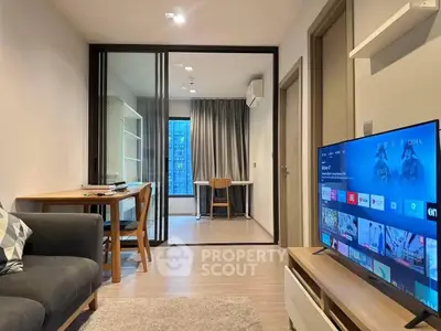 Modern living room with sleek design and large TV, featuring a cozy workspace and floor-to-ceiling windows.