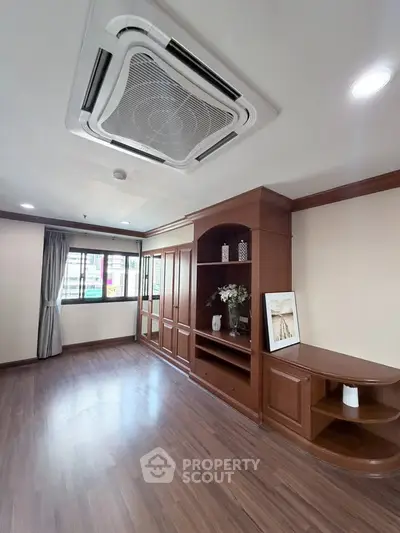 Spacious living room with elegant wooden built-in shelves and modern ceiling air conditioning.