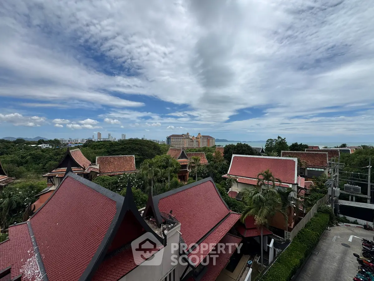 Stunning aerial view of traditional Thai-style rooftops with lush greenery and cityscape in the background.