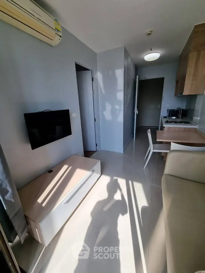 Modern apartment interior with sleek kitchen and cozy living area, featuring natural light and minimalist design.