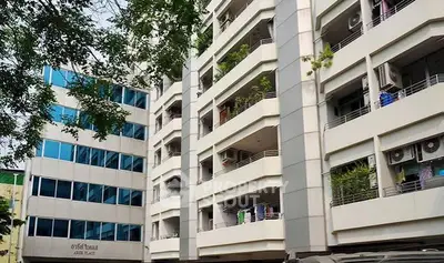 Modern apartment building with balconies and lush greenery in urban setting.