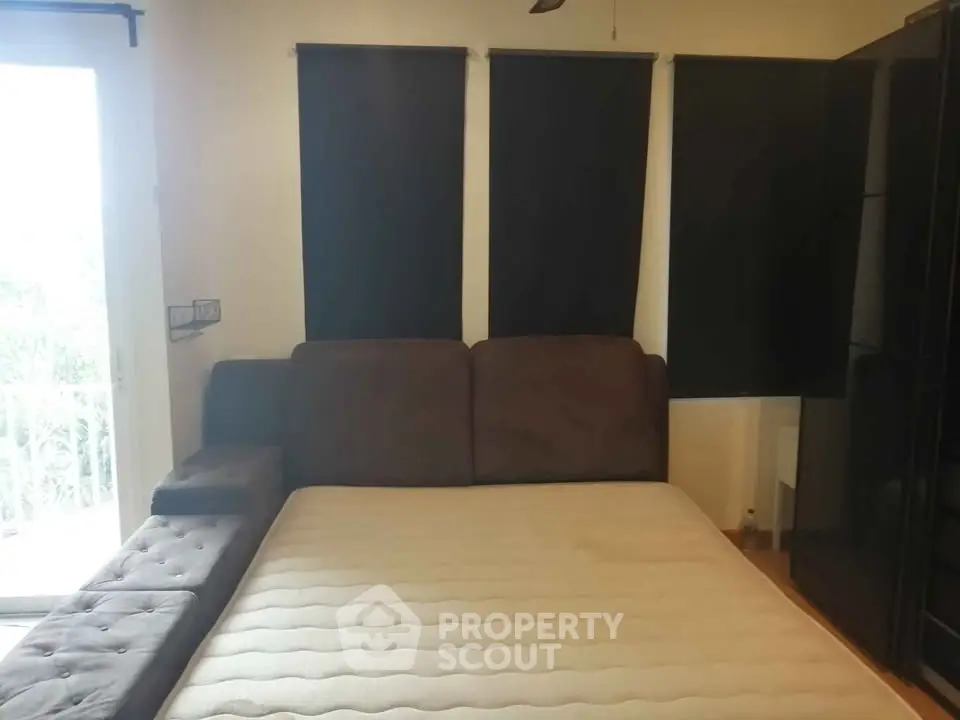 Cozy bedroom with large bed and dark curtains, perfect for restful nights.