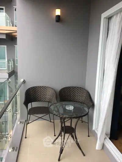 Charming balcony with cozy seating and modern glass railing, perfect for relaxation.