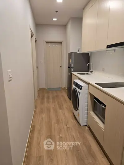 Modern kitchen with sleek appliances and wooden flooring in a compact layout.
