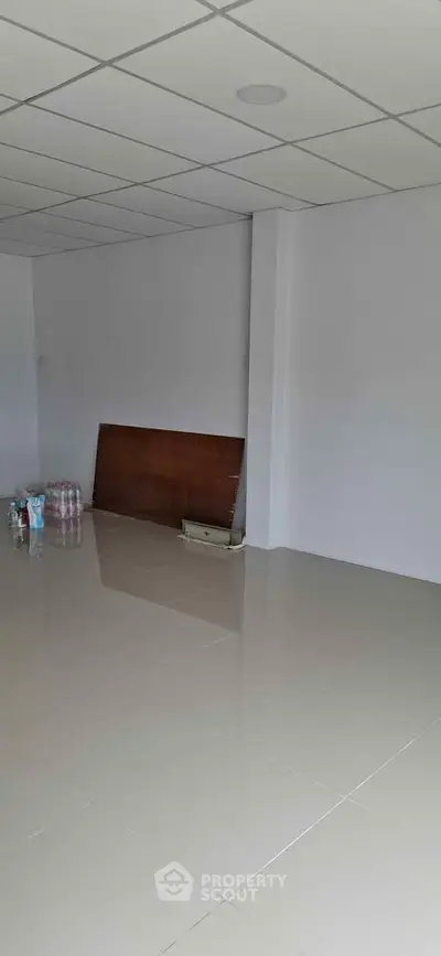 Spacious empty room with tiled flooring and white walls, ideal for customization.