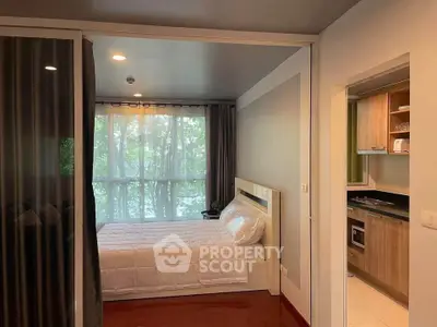 Cozy bedroom with large window and adjacent modern kitchen in stylish apartment.