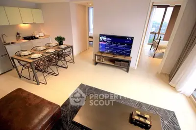 Modern open-plan living room with kitchen and dining area, featuring sleek furniture and natural light.