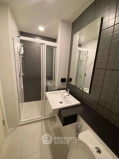 Modern bathroom with sleek shower enclosure and stylish black tile accents.