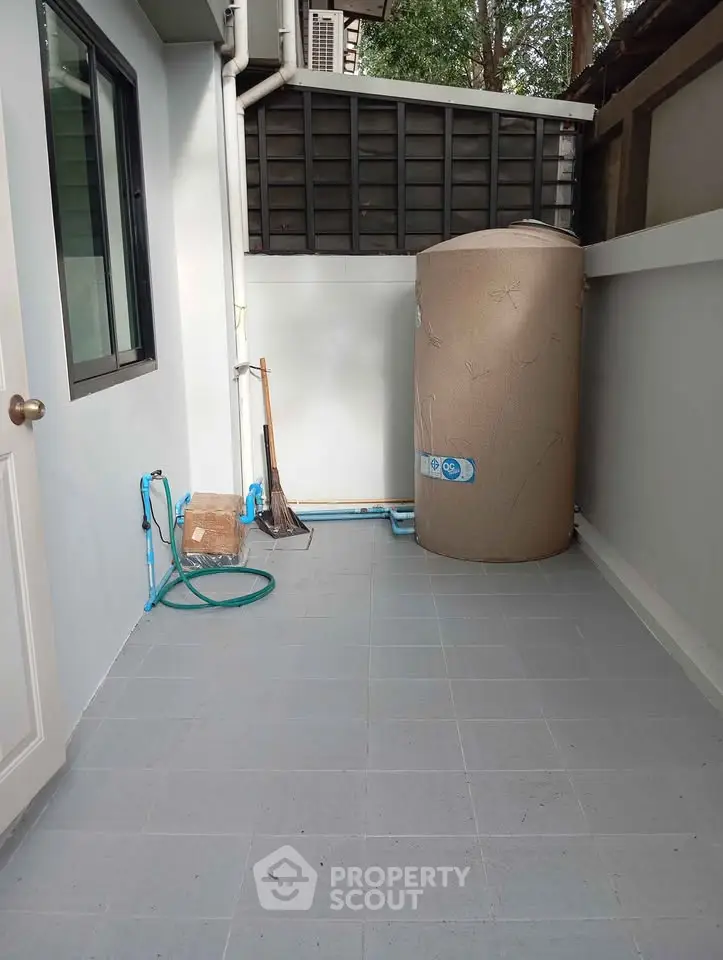 Outdoor utility area with water tank and cleaning tools, ideal for storage or maintenance.