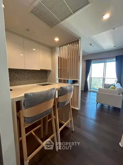 Modern open-plan kitchen and living room with stylish decor and balcony view.