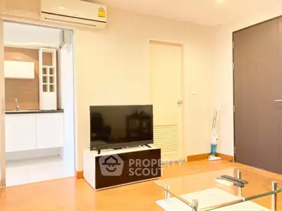 Modern living room with sleek TV setup and open kitchen layout in cozy apartment.