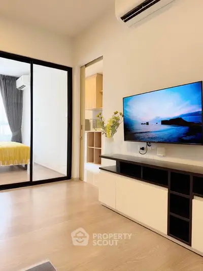 Modern living room with sleek TV setup and view into cozy bedroom