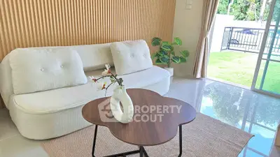Modern living room with stylish sofa, unique coffee table, and garden view through glass doors.