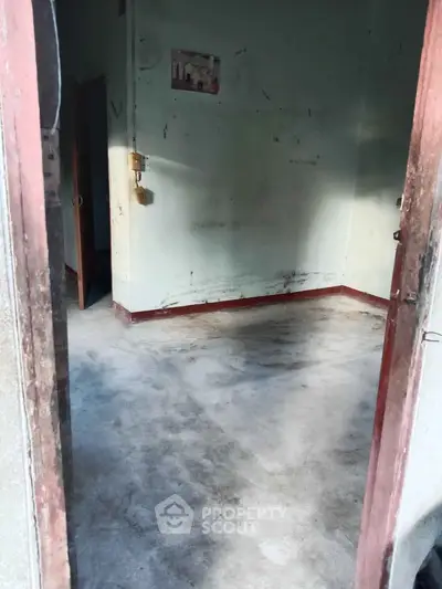 Spacious empty room with potential for renovation, featuring bare walls and concrete flooring.