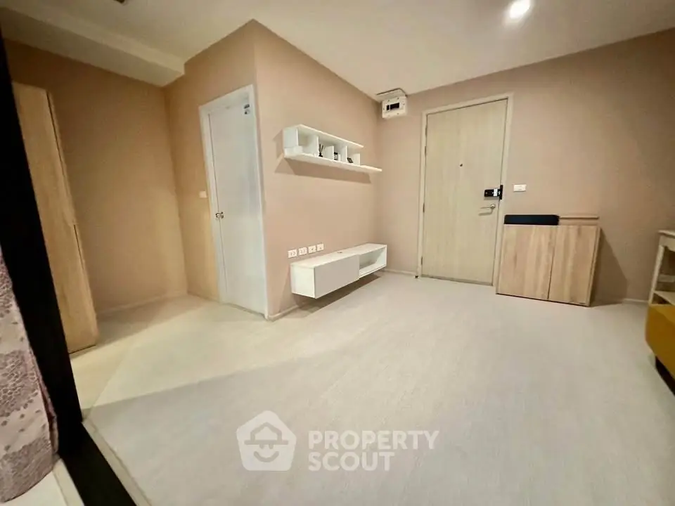 Modern minimalist living room with light wood flooring and sleek storage solutions.