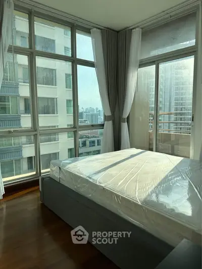 Bright bedroom with large windows offering stunning city views in a modern apartment.