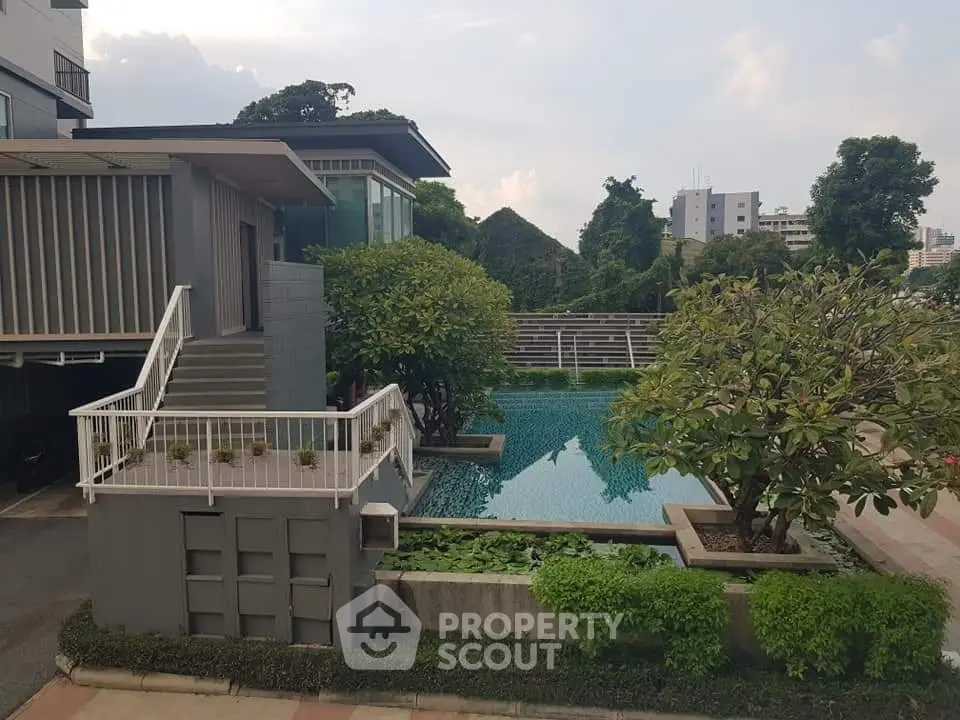 Modern residential building with lush greenery and a serene swimming pool, perfect for relaxation and leisure.