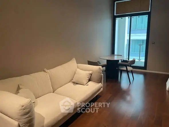 Modern living room with cozy sofa and dining area, featuring large window for natural light.
