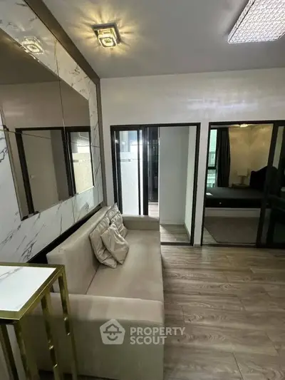 Modern living room with elegant decor and sliding glass doors leading to a bedroom, featuring stylish lighting.