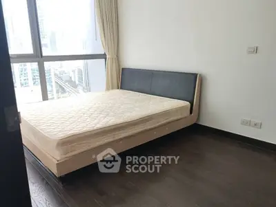 Modern bedroom with large window and city view, featuring a sleek bed and hardwood floors.