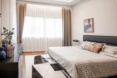 Elegant bedroom with modern decor, featuring a large window with sheer curtains and stylish furnishings.