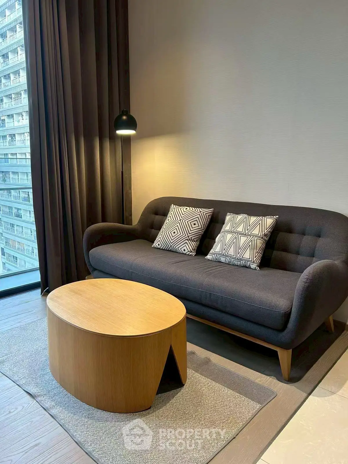 Modern living room with stylish sofa and coffee table, large window view.