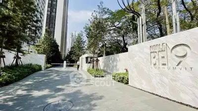 Luxurious entrance of Noble RE9 Sukhumvit with lush greenery and modern architecture.