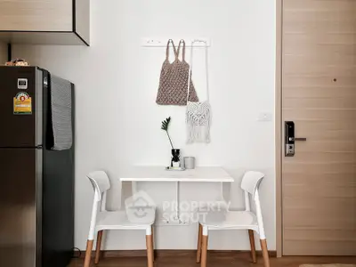 Modern minimalist dining nook with compact table and chairs, adjacent to sleek kitchen appliances.