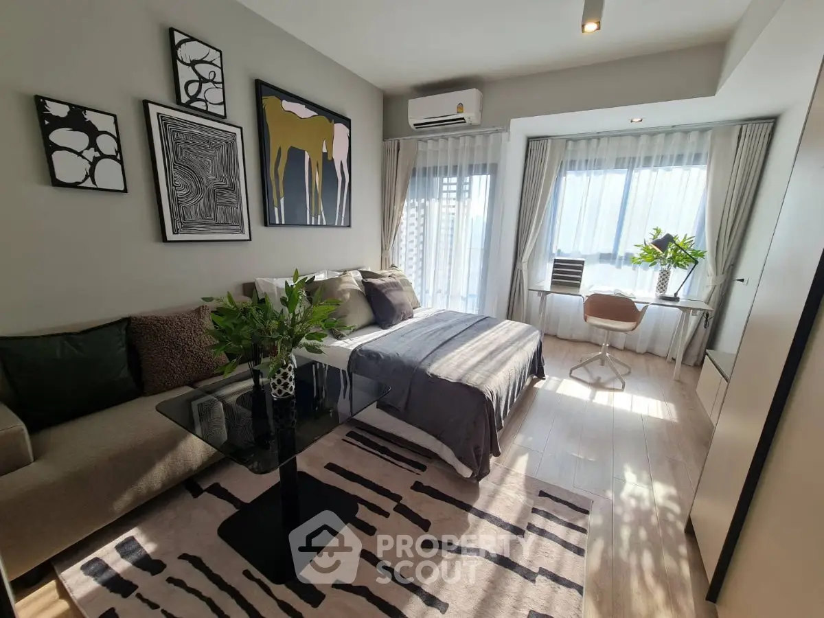 Modern bedroom with stylish decor, large windows, and cozy seating area.