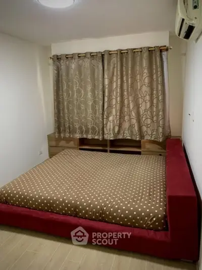 Cozy bedroom with modern decor and plush red bed frame, perfect for relaxation.