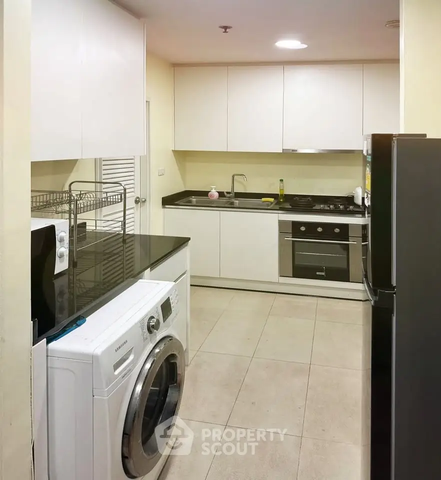 Modern kitchen with sleek appliances and washing machine in a compact layout.