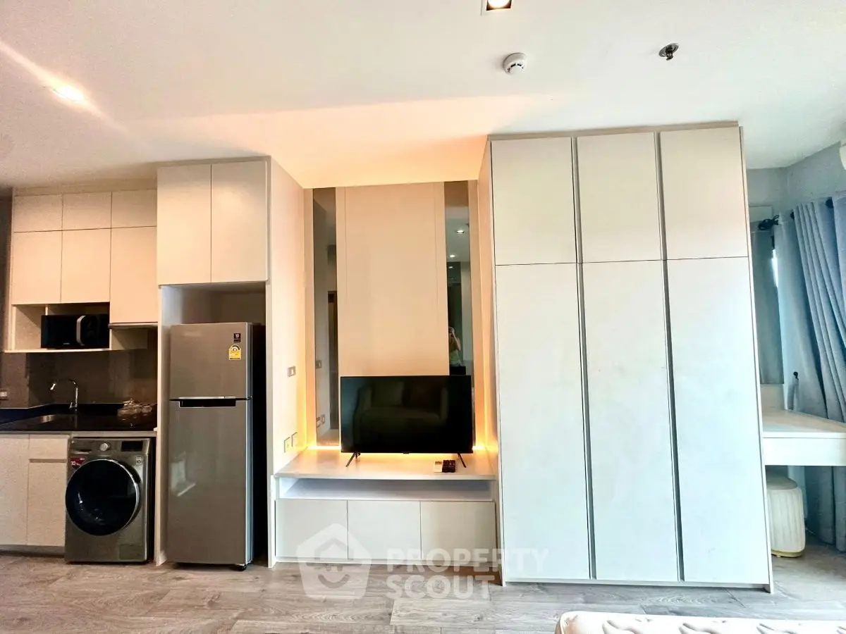 Modern apartment interior with sleek kitchen and integrated living area featuring appliances and stylish cabinetry.