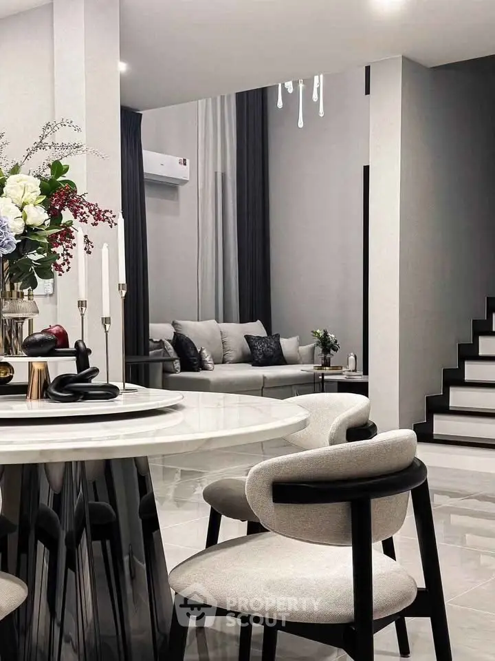 Elegant modern living room with stylish furniture and chic decor, featuring a sleek staircase and cozy seating area.