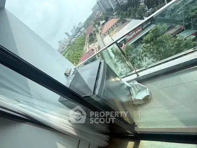 Modern balcony with glass railing and city view, featuring a compact washing machine.