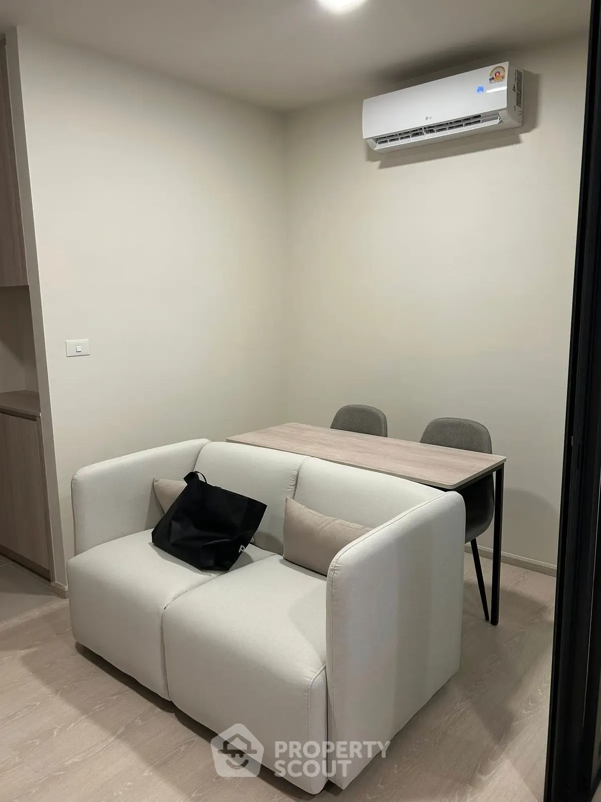 Cozy modern living room with compact sofa and dining table under air conditioning