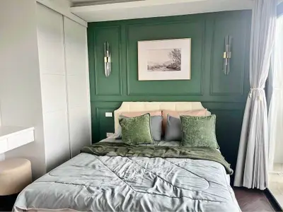 Elegant bedroom with green accent wall and cozy bedding in modern apartment
