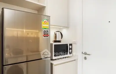 Modern kitchen with stainless steel fridge and microwave in sleek apartment.