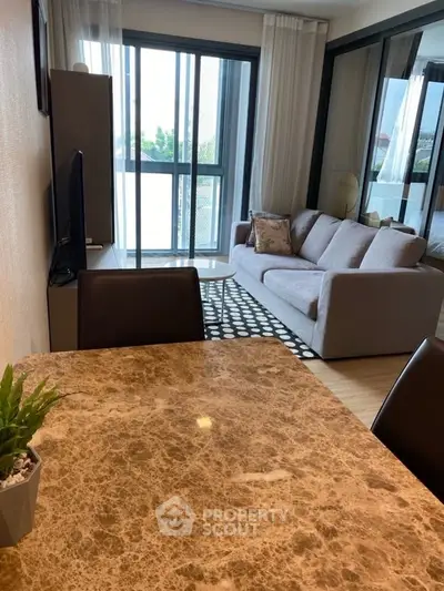 Modern living room with marble dining table and cozy sofa, featuring large windows and natural light.