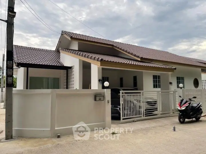 Modern single-story house with tiled roof and gated driveway in a suburban setting.