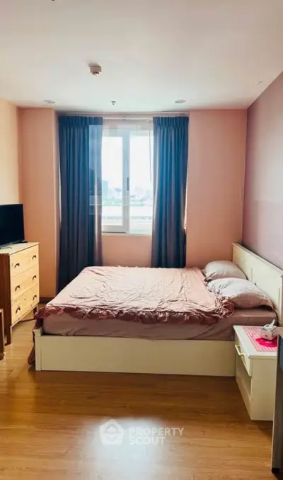 Cozy bedroom with large window and wooden flooring, perfect for relaxation.