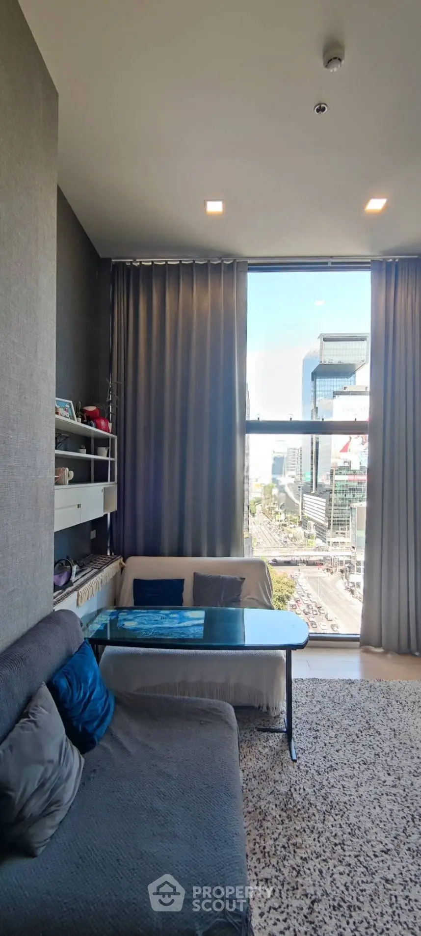 Modern living room with large window offering stunning city view, cozy seating, and elegant decor.
