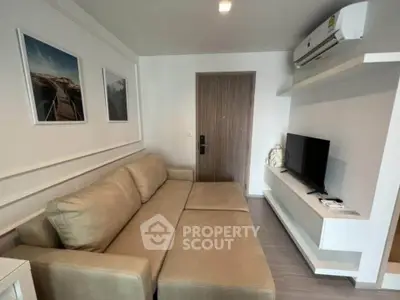 Modern living room with beige sofa, wall-mounted TV, and air conditioning in a stylish apartment.