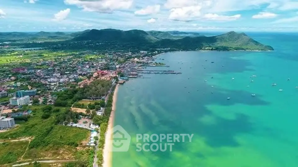 Stunning aerial view of coastal town with lush greenery and pristine beach.