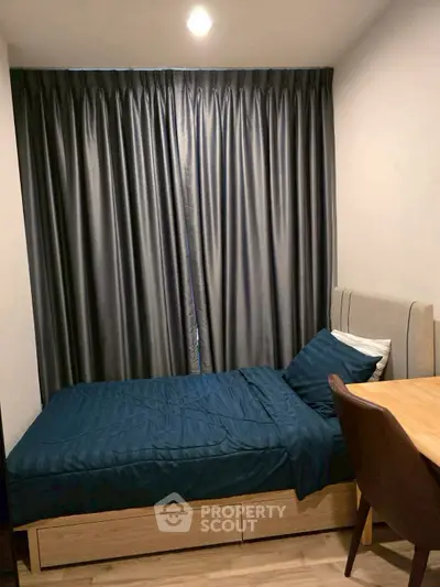 Cozy bedroom with single bed and elegant curtains, perfect for a peaceful retreat.