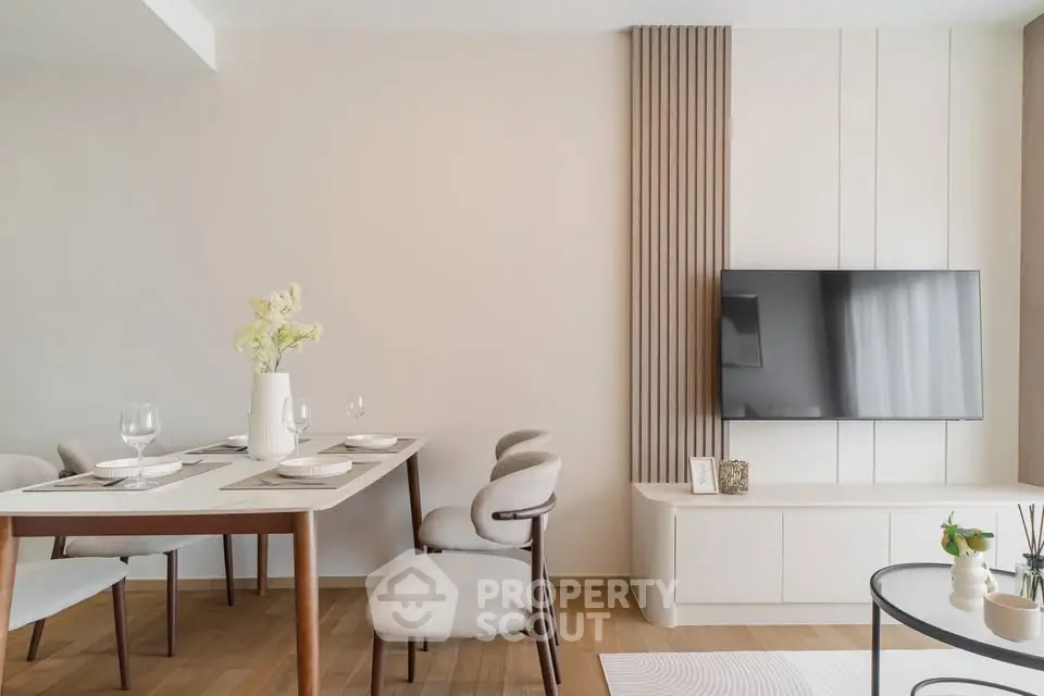 Modern living room with elegant dining area and wall-mounted TV, featuring minimalist decor and wooden flooring.