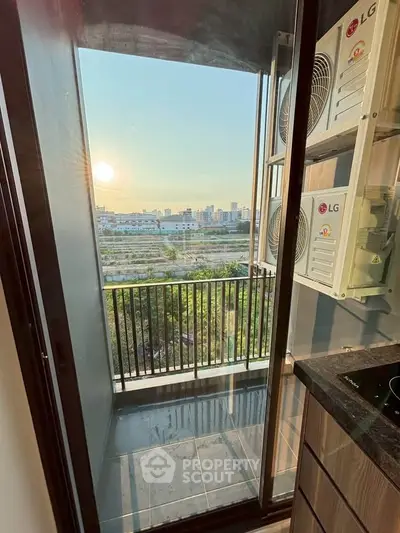 Modern balcony with city view and sunset, featuring sleek design and air conditioning units.