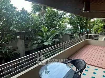 Spacious balcony with lush greenery view, perfect for relaxation and outdoor dining.