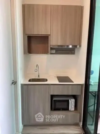 Compact modern kitchen with sleek cabinetry and built-in appliances in a cozy apartment.