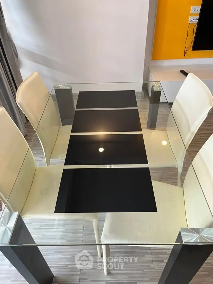 Modern glass dining table with sleek black accents and white chairs in a contemporary setting.